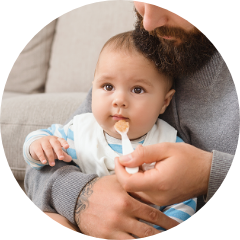 Bebé en los brazos de un hombre alimentando al bebé con una cuchara